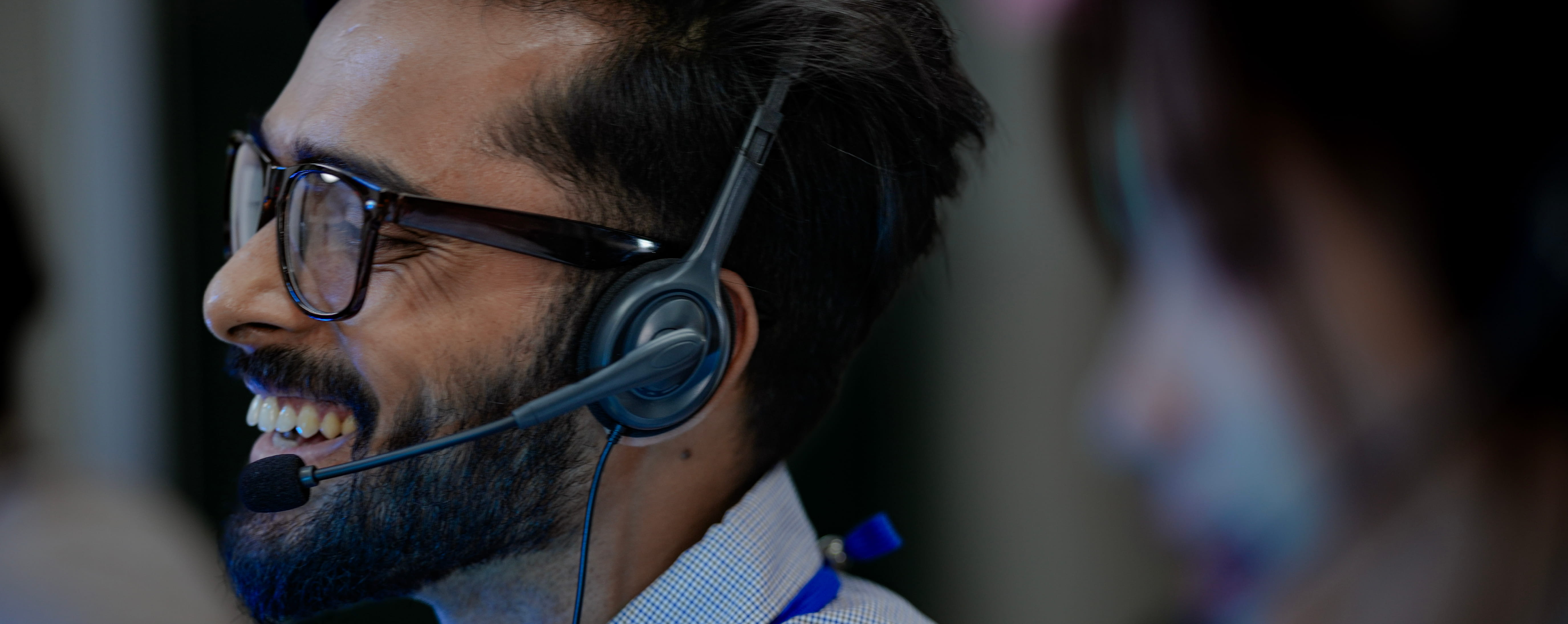 Male contact center employee wearing a headsrt, smiling on a call.