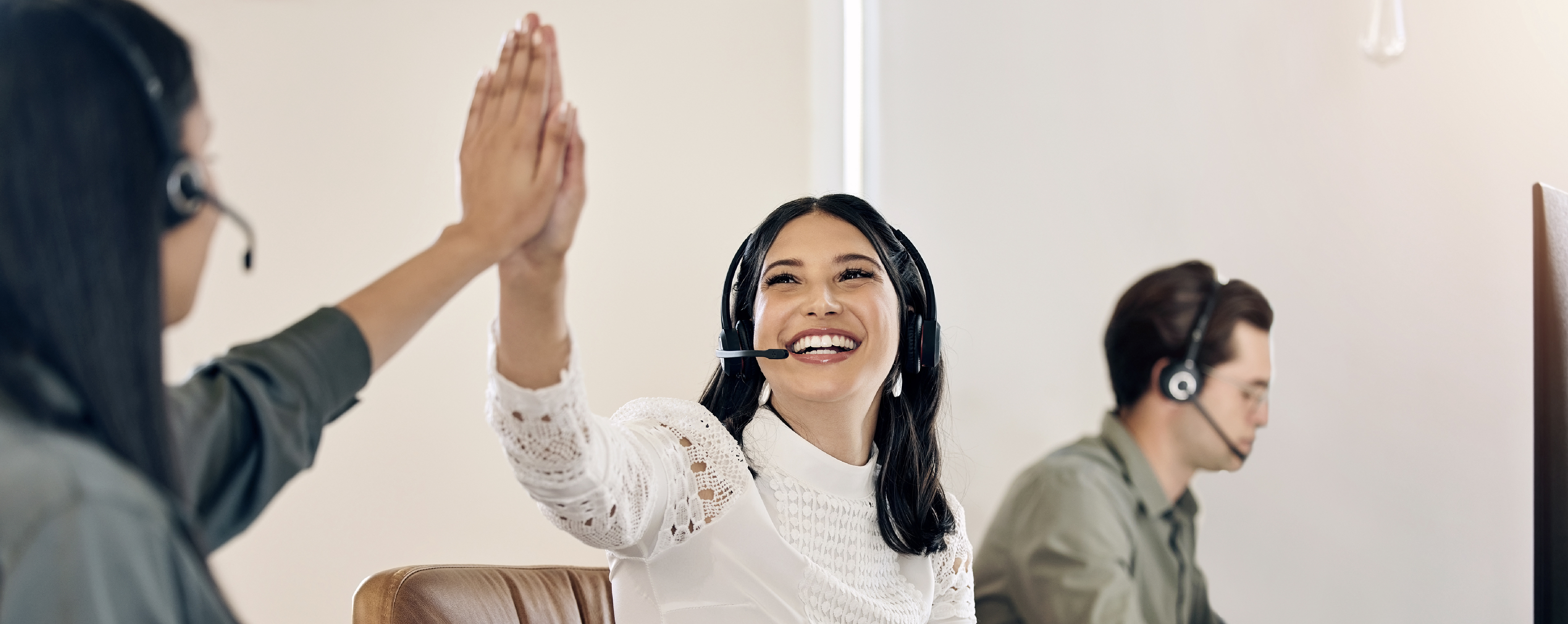Call center employees high-fiving after successfully helping a customer.
