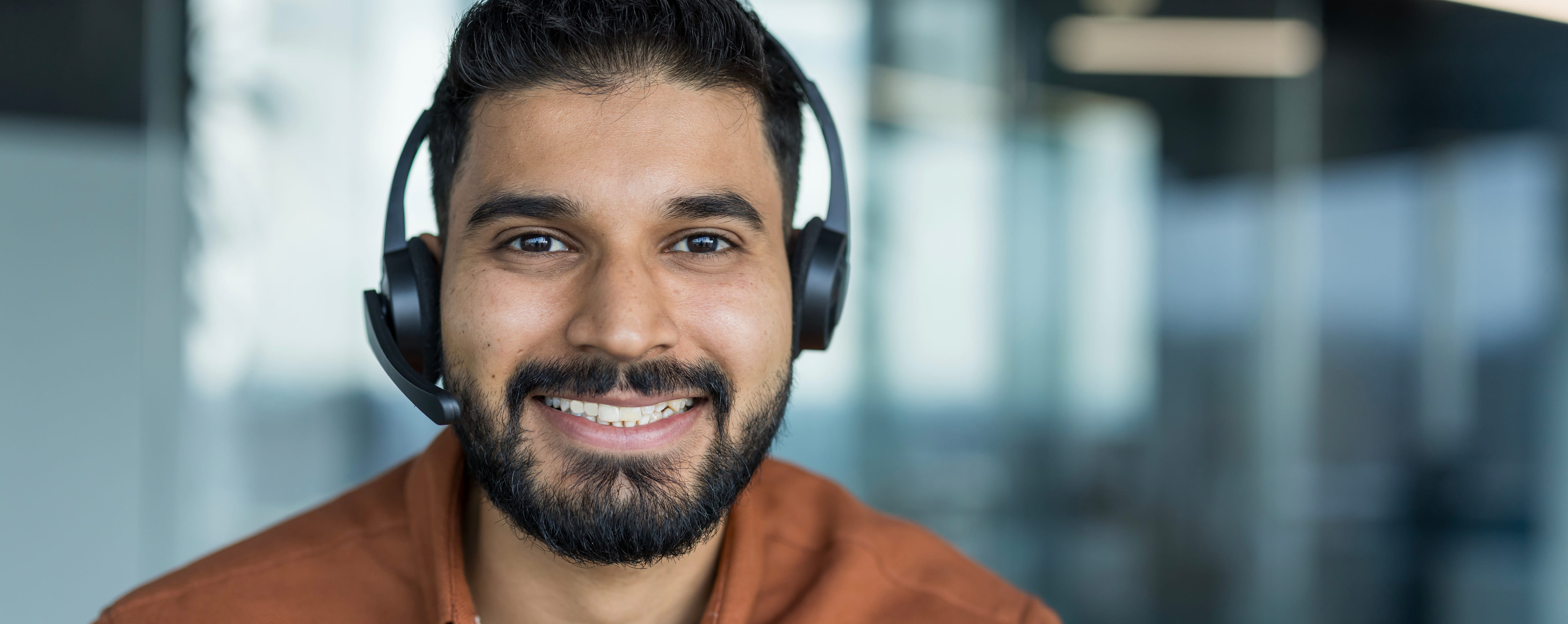 Contact center agent smiling at the camera with a headset on.