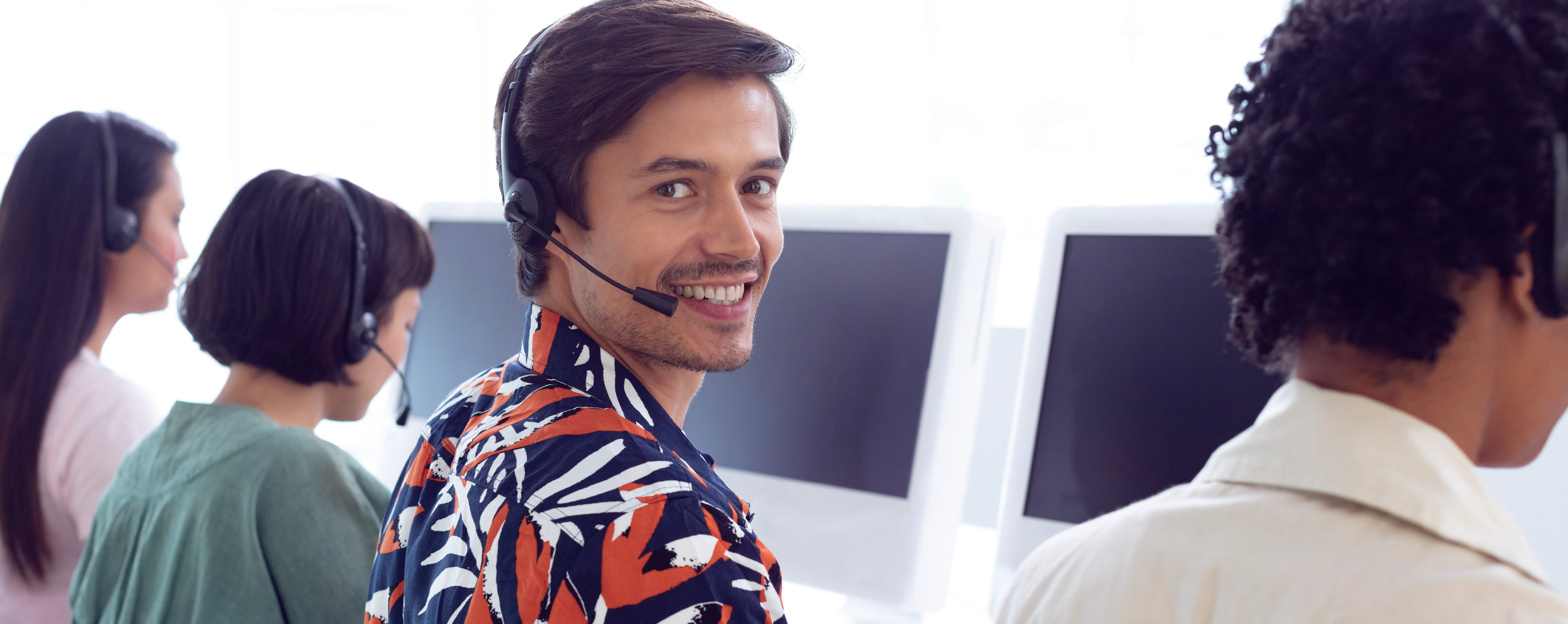 Contact center agent sitting with his colleagues in an office setting.