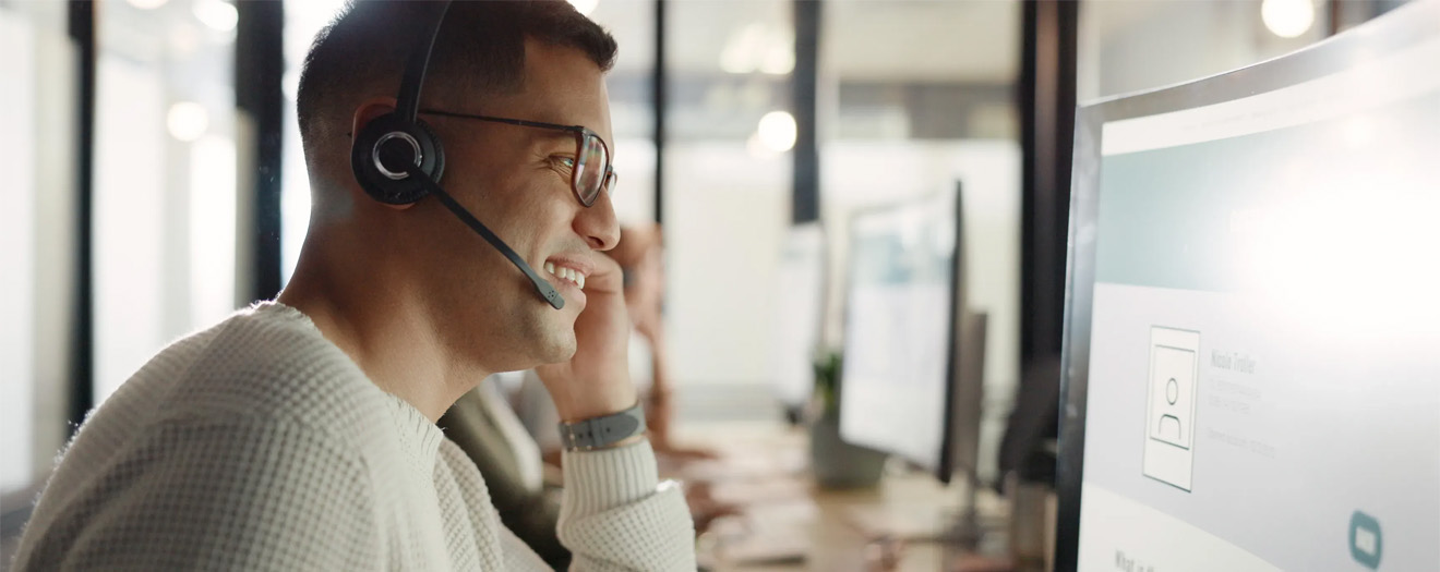 Contact center agent wearing a headset while using AI-powered software on a desktop monitor.