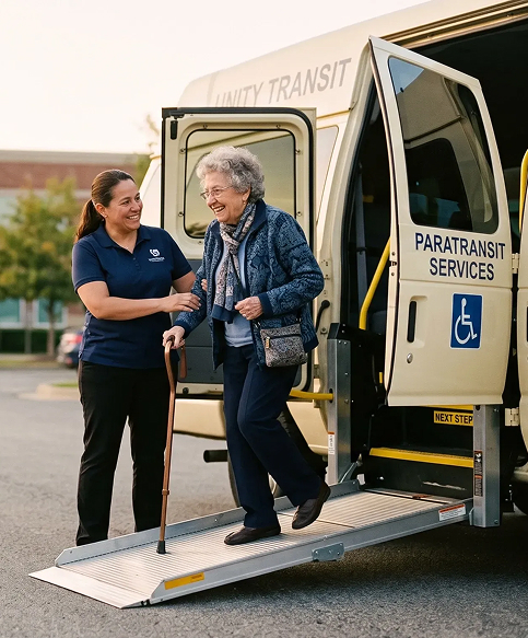 Paratransit driver assisting an elderly passenger with a cane down a wheelchair-accessible van ramp