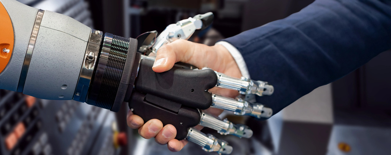 Robotic arm shaking hands with a businessperson, representing AI and human collaboration