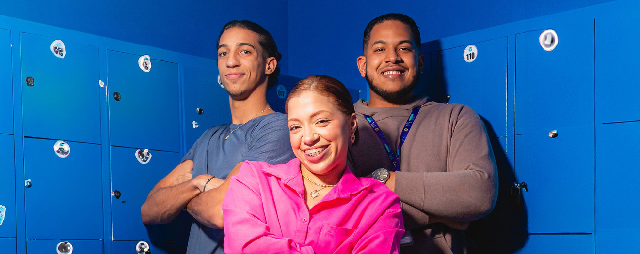 Three smiling young adults standing in front of blue school lockers