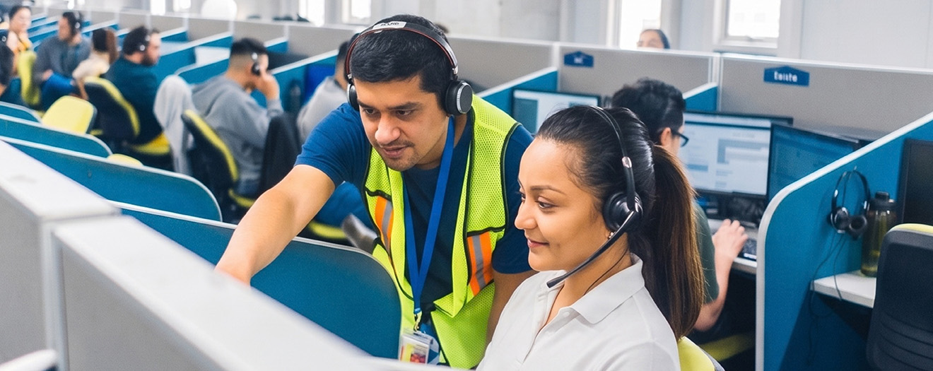 Team Lead coaching a contact center agent at her workstation