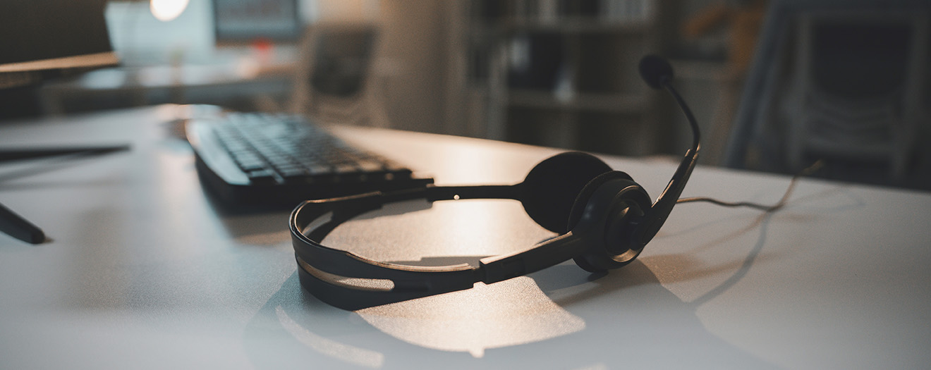 Contact center headset resting on an empty desk next to a keyboard